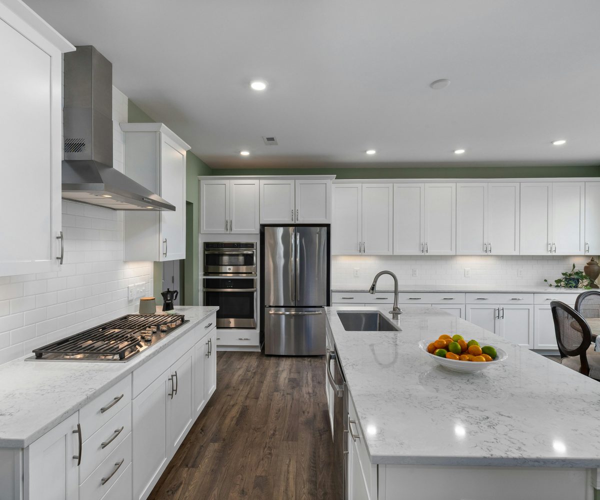 Bright white kitchen with a long marble-style island and stainless appliances