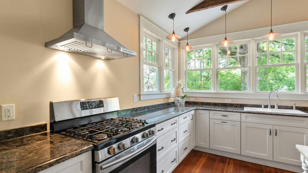 Sunlit kitchen with tall windows, pendant lights and a gas range